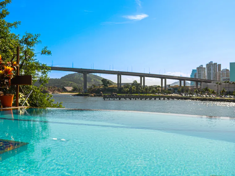 Piscina de borda infinita com a baía e a Terceira Ponte ao fundo