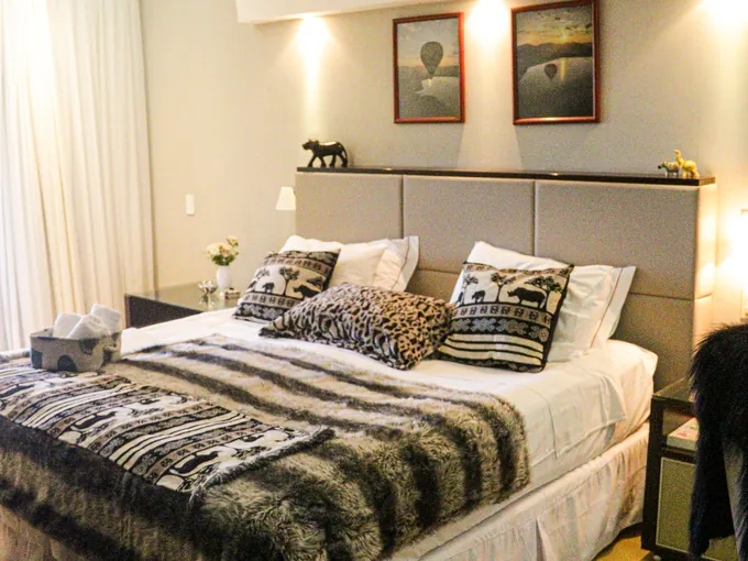Suíte com cama arrumada e tecidos africanos sobre a colcha