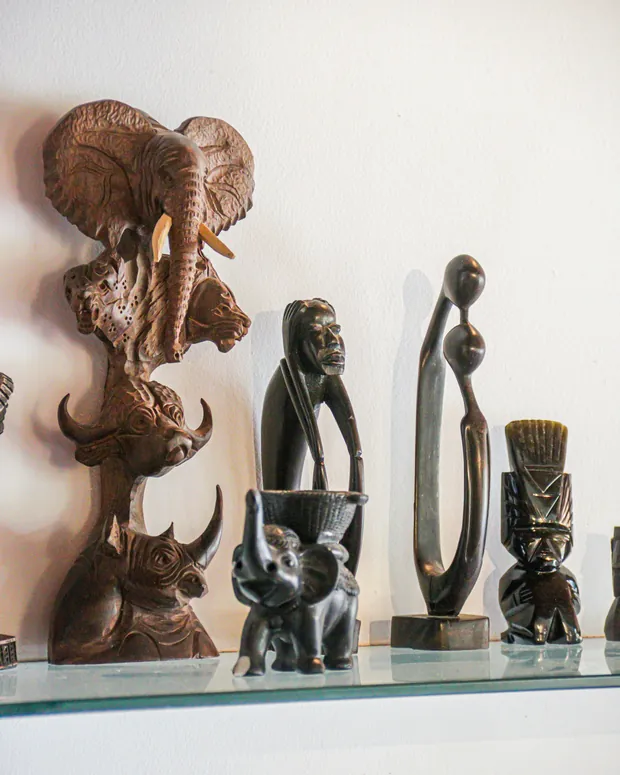 Peças entalhadas sobre o balcão da sala: elefante, rinoceronte e figuras africanas